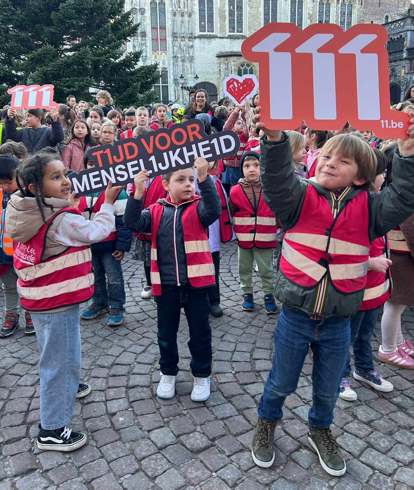 Kinderen houden de pancarte 'Tijd voor menselijkheid' omhoog tijdens de persactie in Brugge