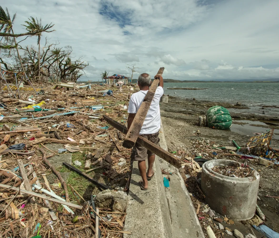 Man verzamelt hout voor de heropbouw na de passage van tyfoon Haiyan in de Filipijnen