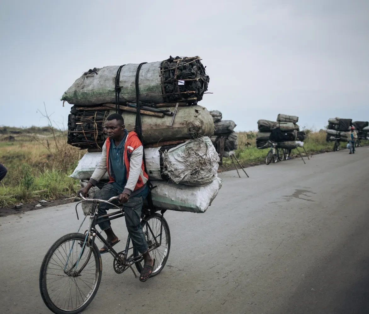 Een fietsendrager fietst met een lading van ongeveer 300 kilogram houtskool