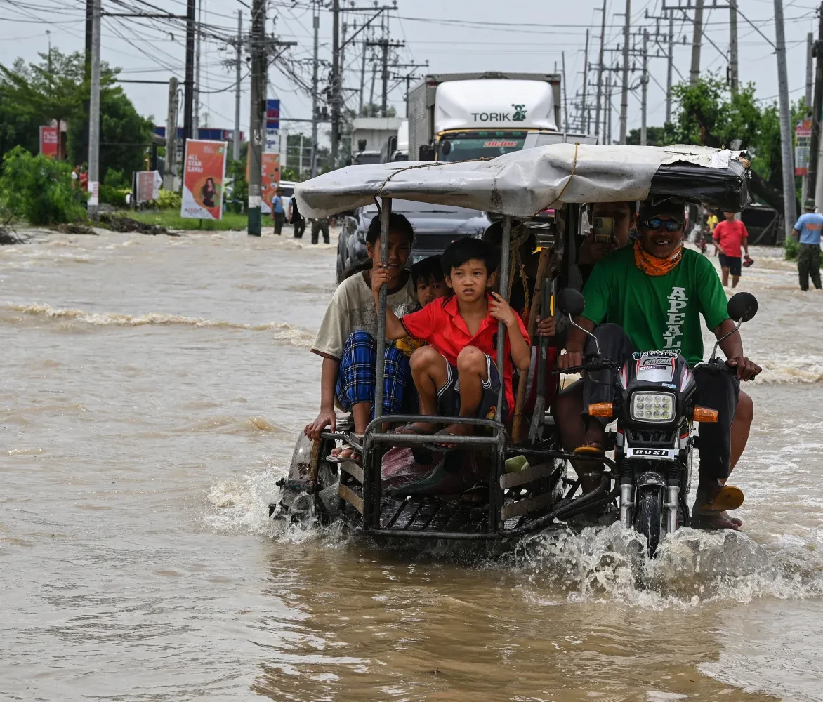 Bewoners en automobilisten pendelen langs een overstroomde snelweg in de nasleep van Super Tyfoon Noru in San Ildefonso, provincie Bulacan