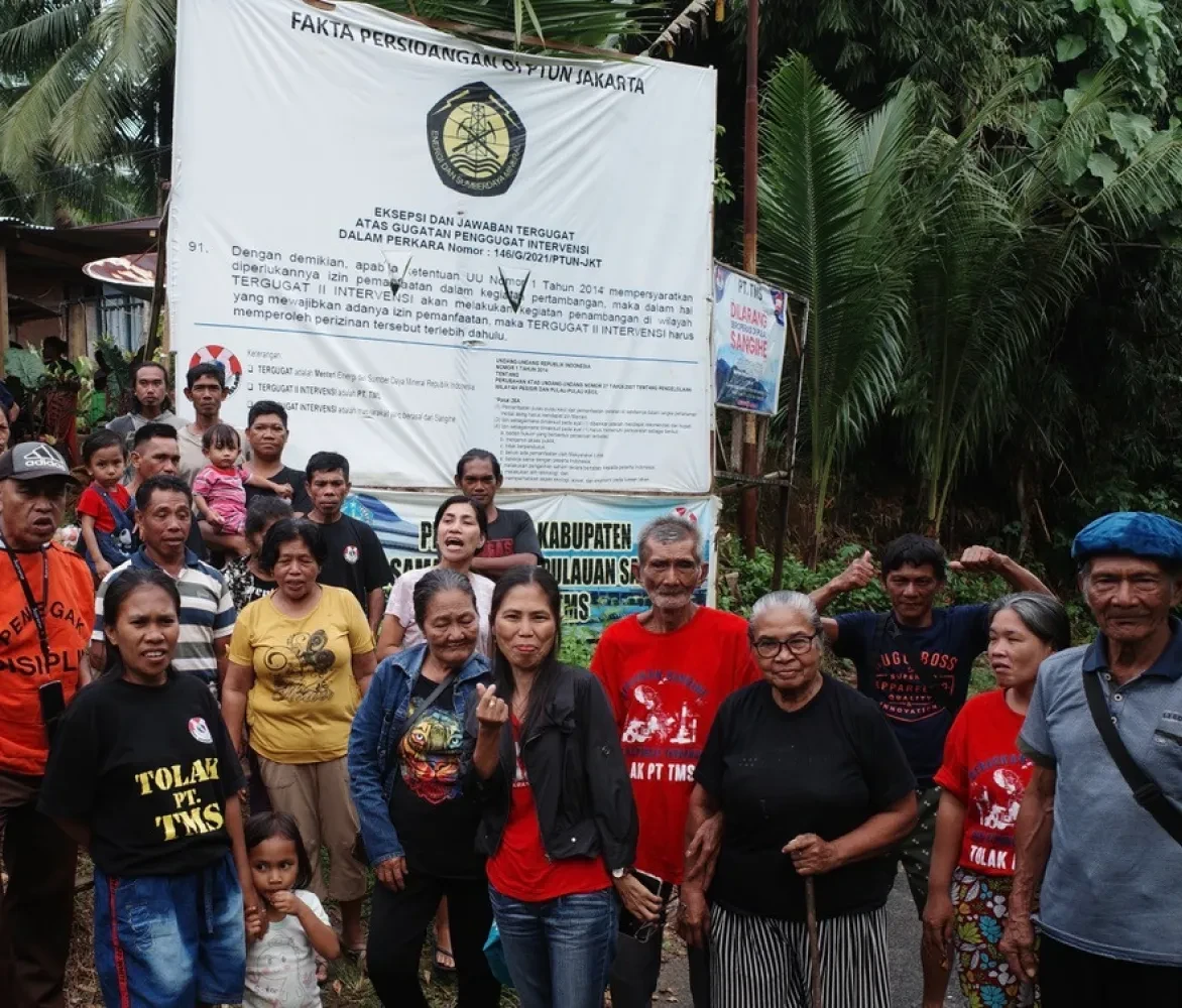  Eilandbewoners voor een spandoek met de print van het arrest van de rechtbank in Jakarta