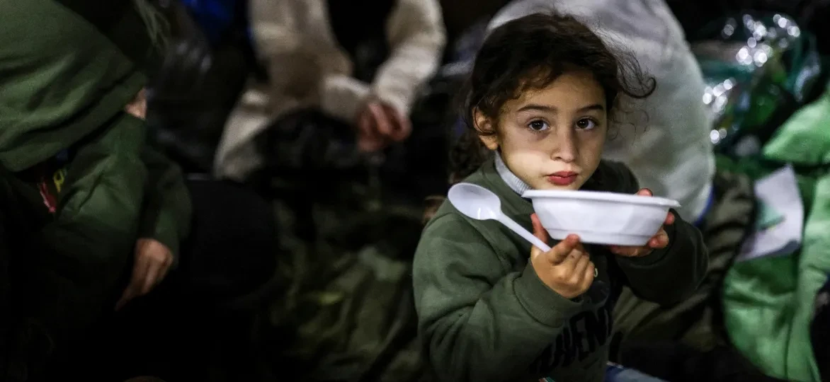 Vluchtelingenkind met bordje in Wit-Rusland nabij de grens met Polen