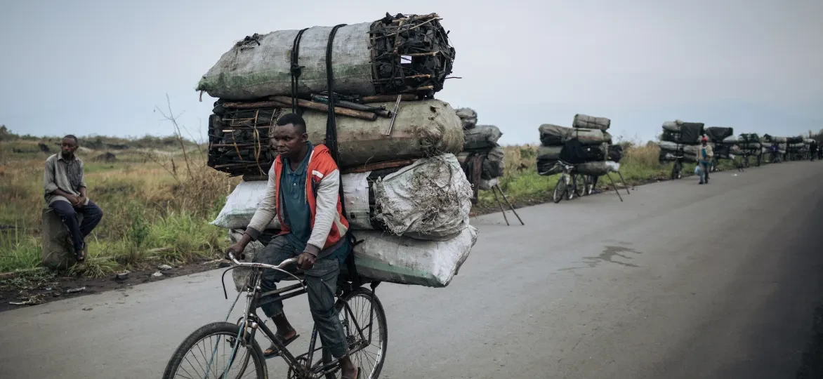 Een fietsendrager fietst met een lading van ongeveer 300 kilogram houtskool