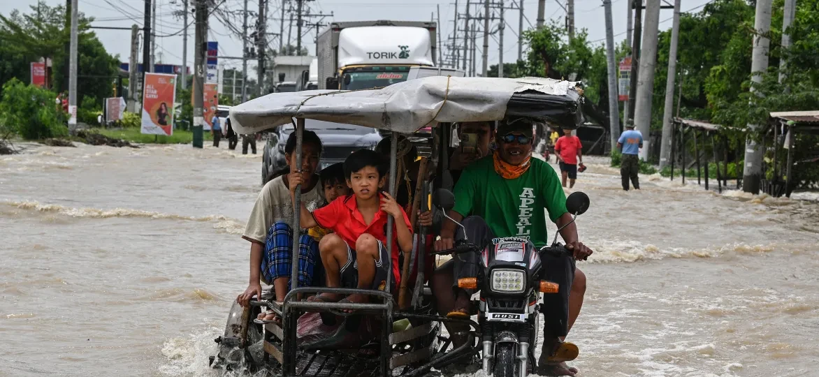 Bewoners en automobilisten pendelen langs een overstroomde snelweg in de nasleep van Super Tyfoon Noru in San Ildefonso, provincie Bulacan