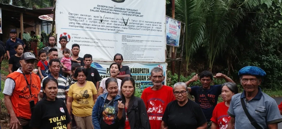  Eilandbewoners voor een spandoek met de print van het arrest van de rechtbank in Jakarta