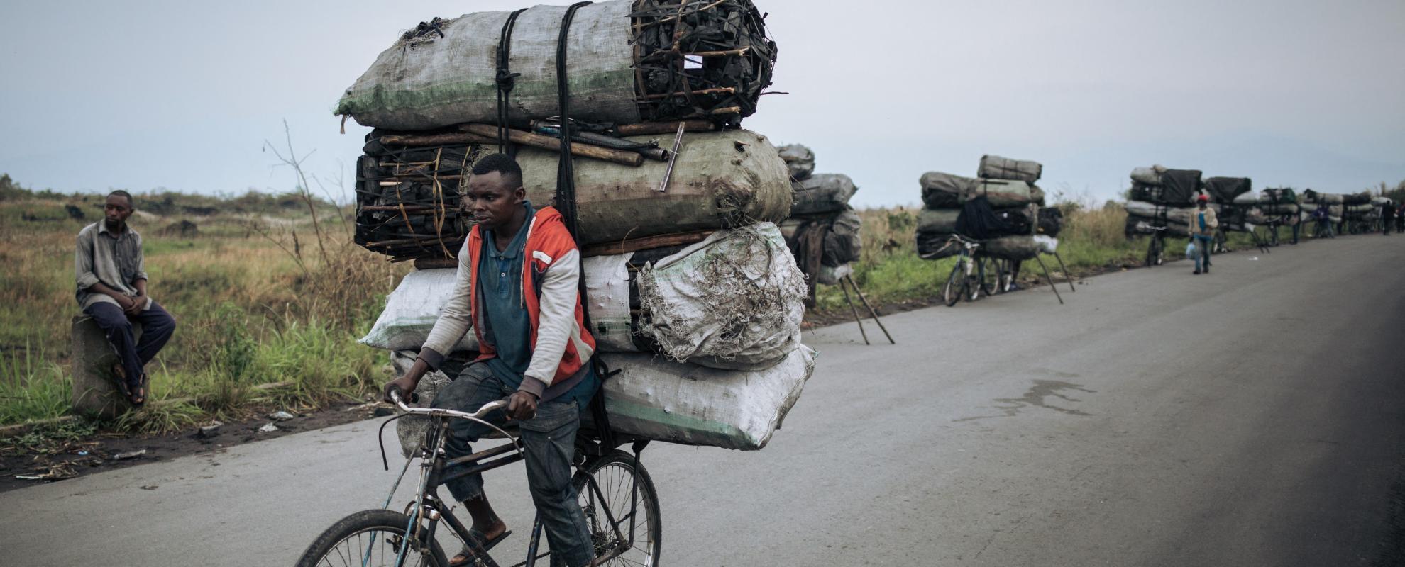 Een fietsendrager fietst met een lading van ongeveer 300 kilogram houtskool