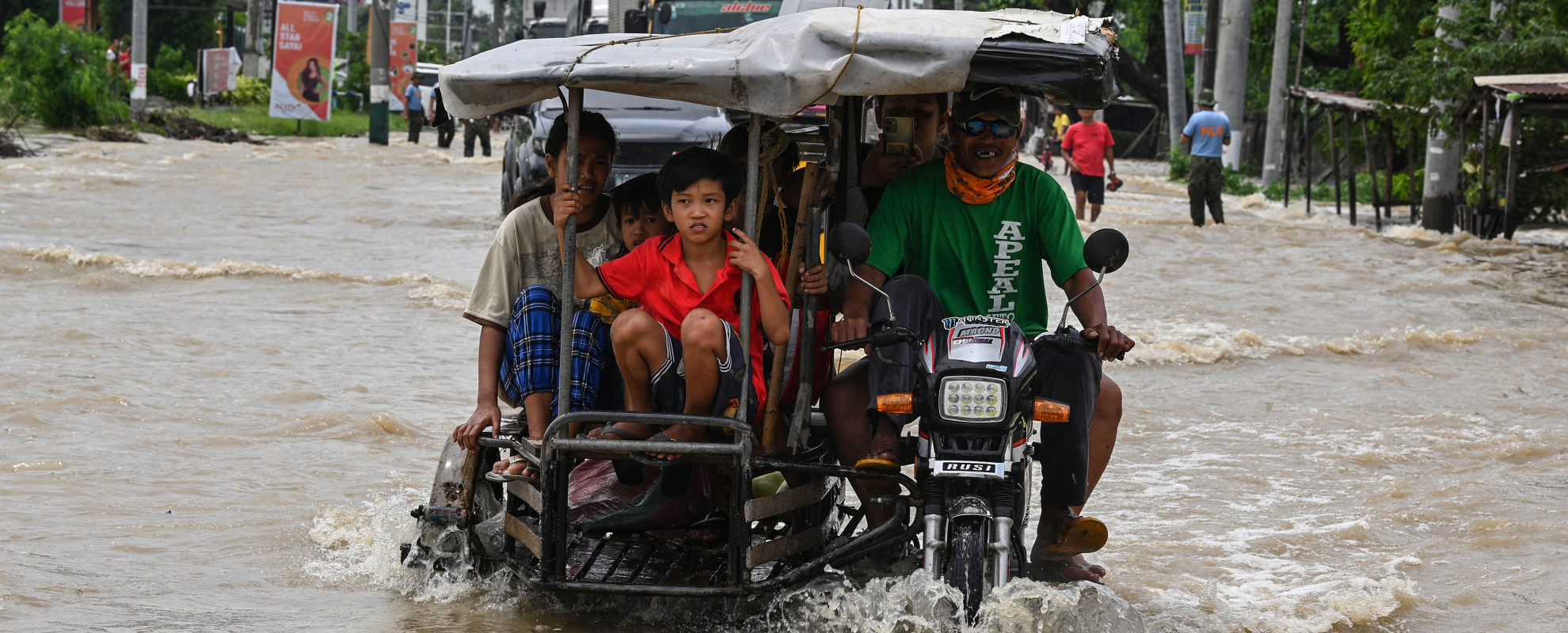 Bewoners en automobilisten pendelen langs een overstroomde snelweg in de nasleep van Super Tyfoon Noru in San Ildefonso, provincie Bulacan