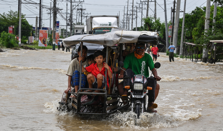 Bewoners en automobilisten pendelen langs een overstroomde snelweg in de nasleep van Super Tyfoon Noru in San Ildefonso, provincie Bulacan