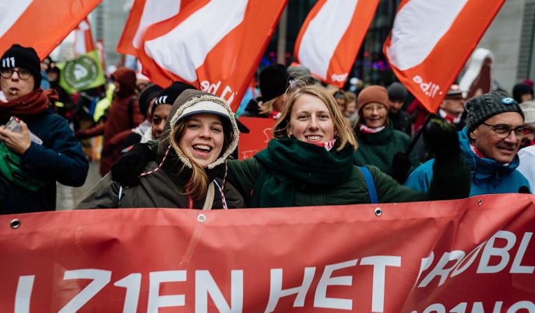 Groep mensen met 11.11.11 vlaggen tijdens de klimaatmars van december 2023