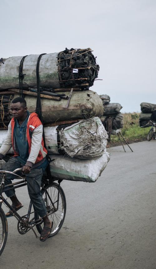 Een fietsendrager fietst met een lading van ongeveer 300 kilogram houtskool