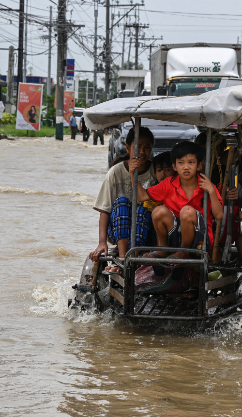 Bewoners en automobilisten pendelen langs een overstroomde snelweg in de nasleep van Super Tyfoon Noru in San Ildefonso, provincie Bulacan