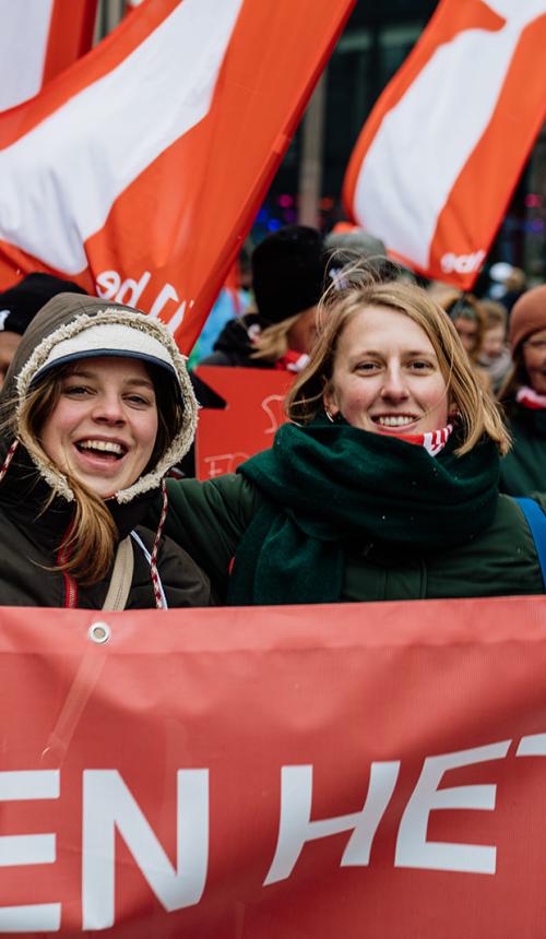 Groep mensen met 11.11.11 vlaggen tijdens de klimaatmars van december 2023