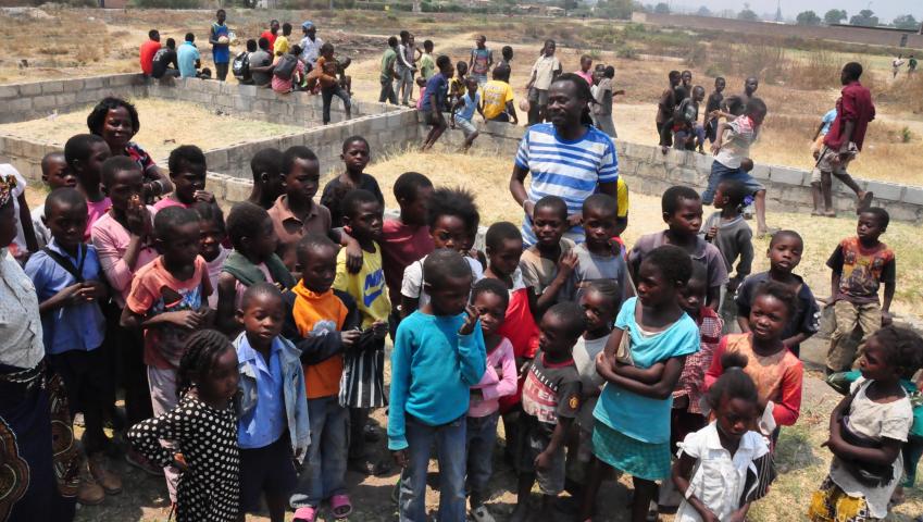 De bezieler van het project Unisport Academy, Geoffrey Msiska, met de kinderen op het terrein (Foto: Steunwielekes4Zambia)