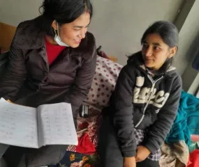 Een meisje met een beperking, samen met haar fieldworker.