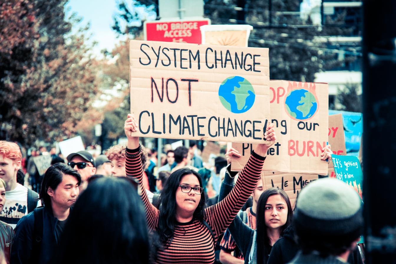 Jonge klimaatactivisten met een bord 'system change, not climate change'
