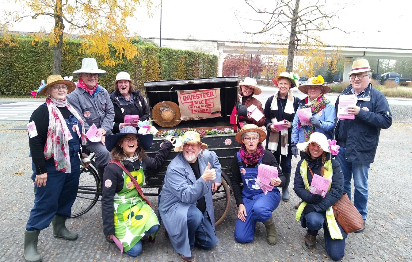 Groep enthousiaste vrijwilligers in 'tuinkledij' en fietskar