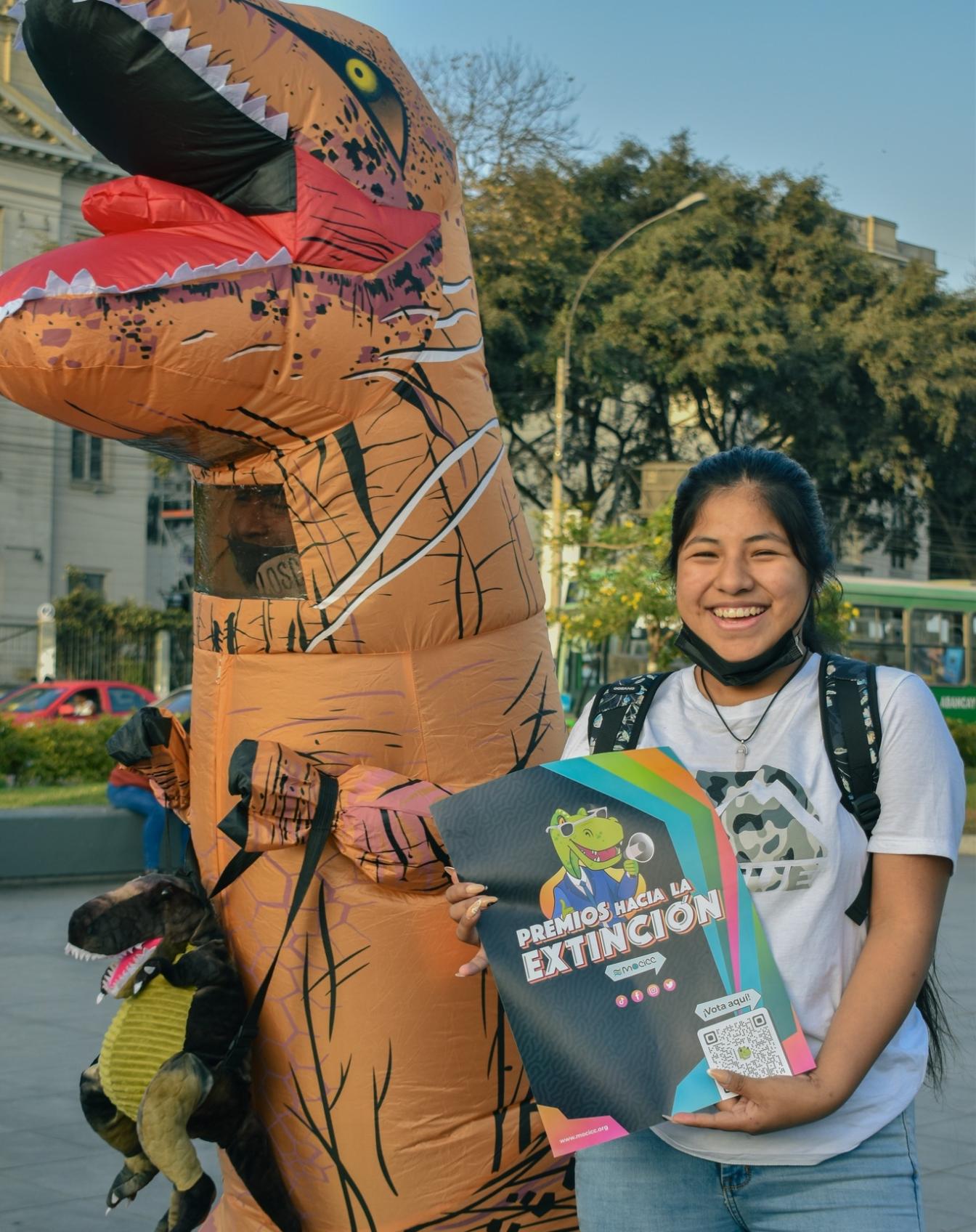 Dinosaurus en meisje met affiche 'Premios hacia la Extinción'