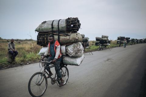 Een fietsendrager fietst met een lading van ongeveer 300 kilogram houtskool