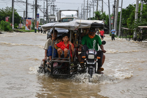 Bewoners en automobilisten pendelen langs een overstroomde snelweg in de nasleep van Super Tyfoon Noru in San Ildefonso, provincie Bulacan