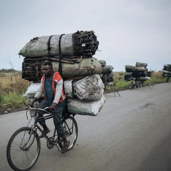 Een fietsendrager fietst met een lading van ongeveer 300 kilogram houtskool