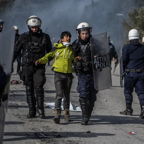 Een migrant wordt hardhandig opgepakt door de Griekse politie in Lesbos